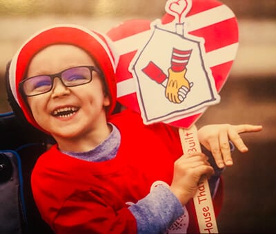 Boy enthusiastically holding a Ronald McDonald's House sign